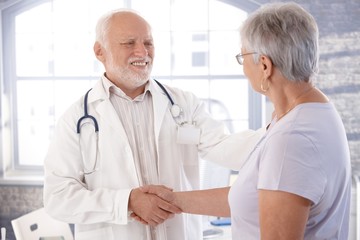 Wall Mural - Mature doctor and senior patient shaking hands