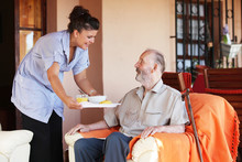 Elderly Senior Being Brought Meal By Carer Or Nurse