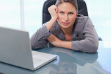 Fototapeta Tulipany - Serious businesswoman leaning on her desk