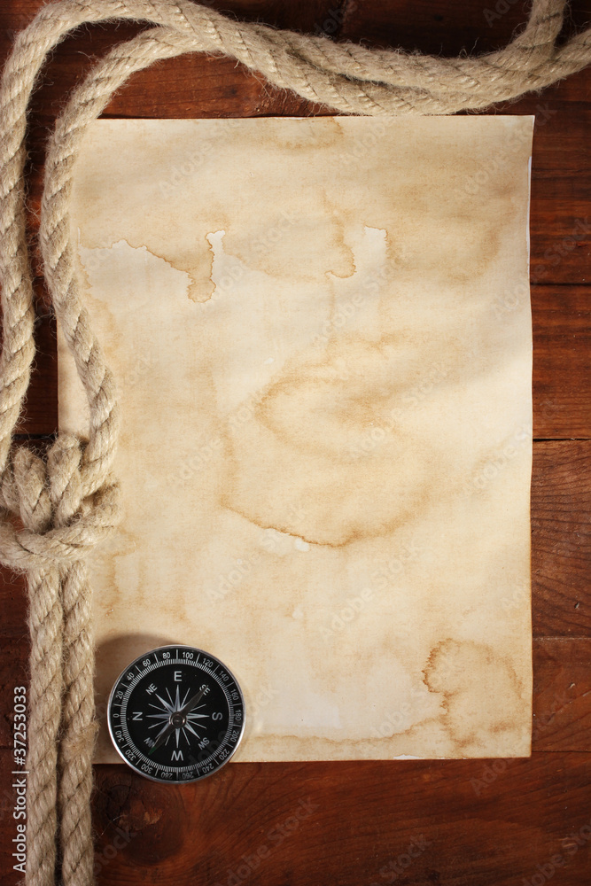 old paper, compass and rope on a wooden table
