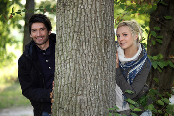 a man and a  woman posing near a tree