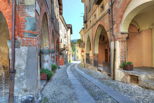 Board z aluminiowym obramowaniem Stara wąska ulica wśród antycznych domów w Avigliana, Italy.