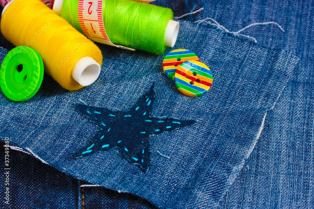 Star-shaped patch on jeans with threads and buttons closeup