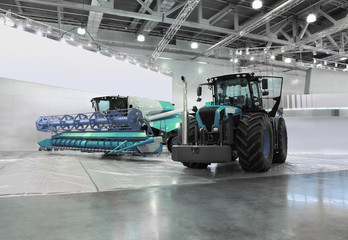 Big tractor and harvester are in room at exhibition