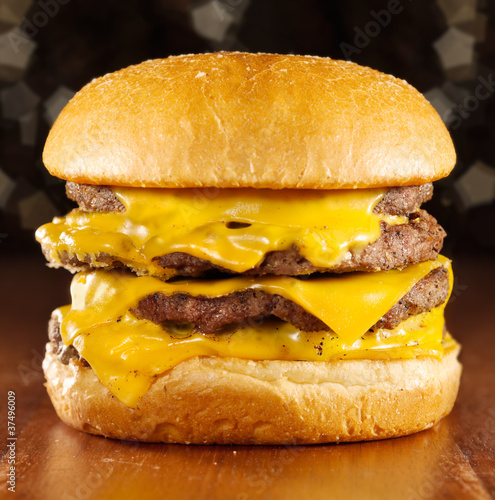 Board z aluminiowym obramowaniem Duży cheeseburger z topionym serem i błyszczącym tle.