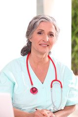 Medic in scrubs working at a desk