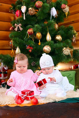 Two baby girls playing with Christmas gifts