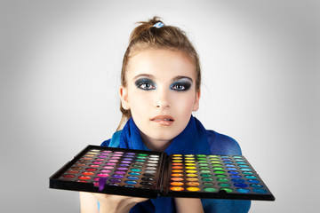 A girl admires make-up collection for creative visage.