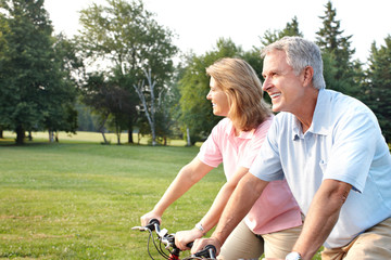 Poster - Senior couple cycling in park.