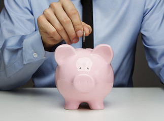 Sticker - Male hand putting coin into a piggy bank