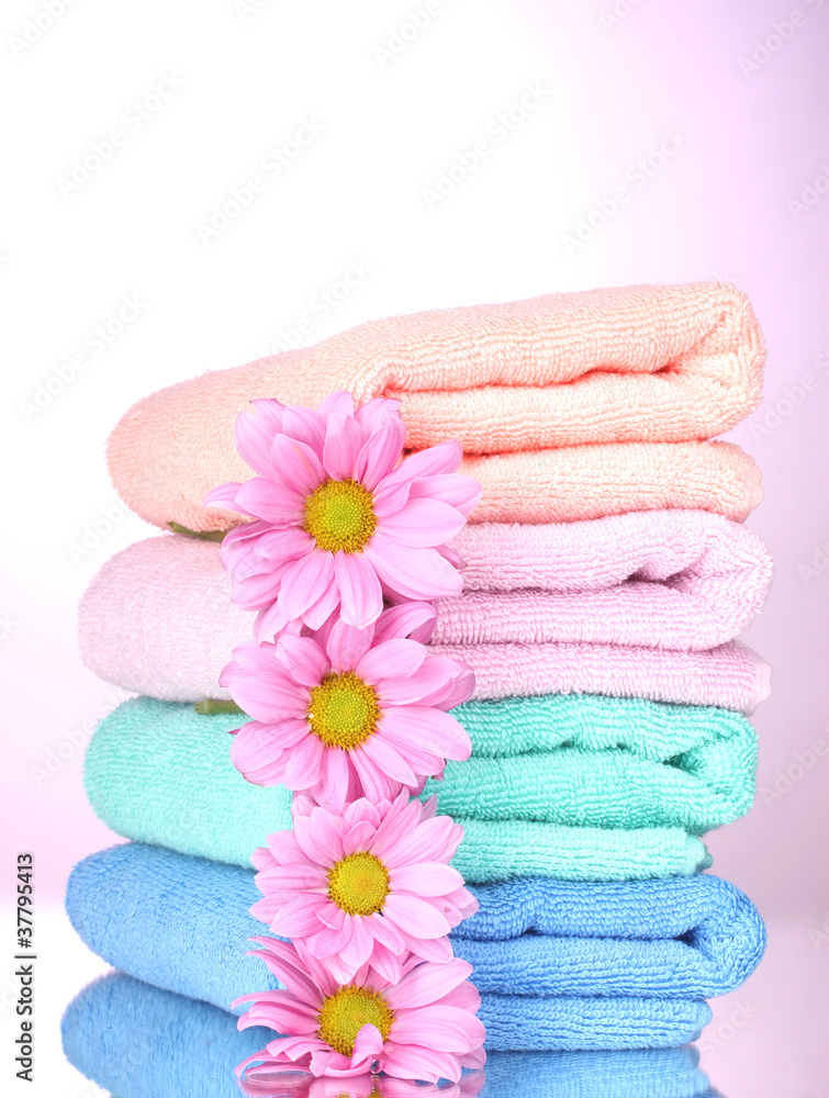 towels and beautiful flowers on pink background