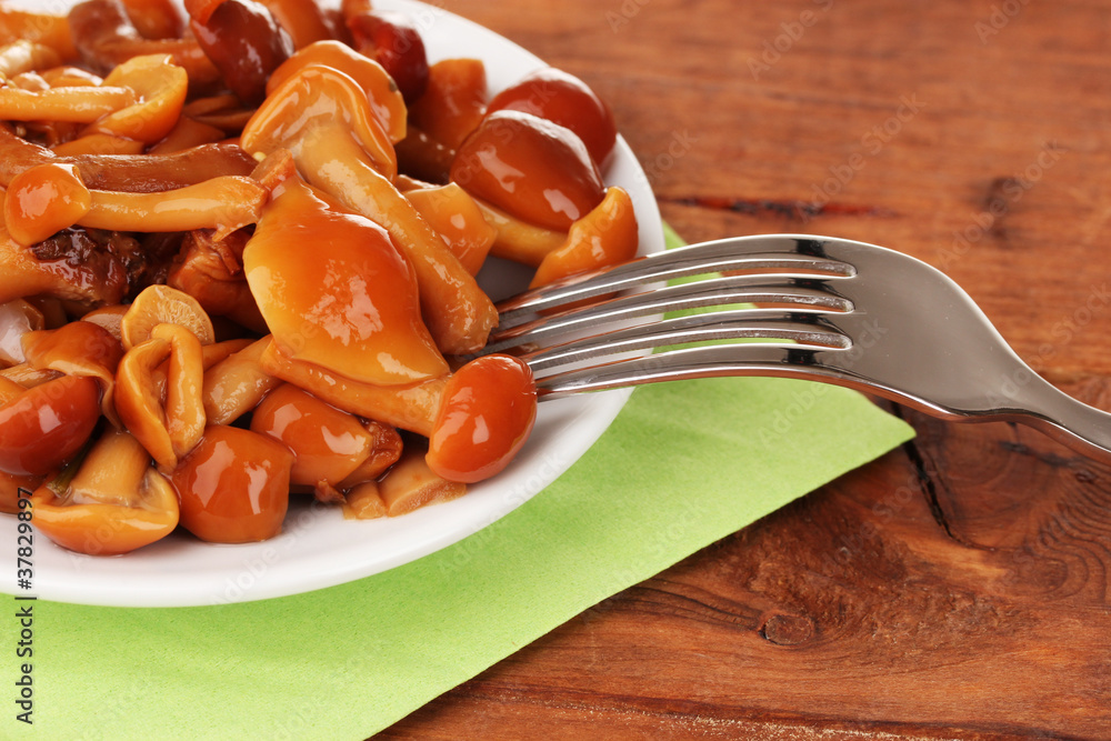 Marinated mushrooms in saucer on wooden table