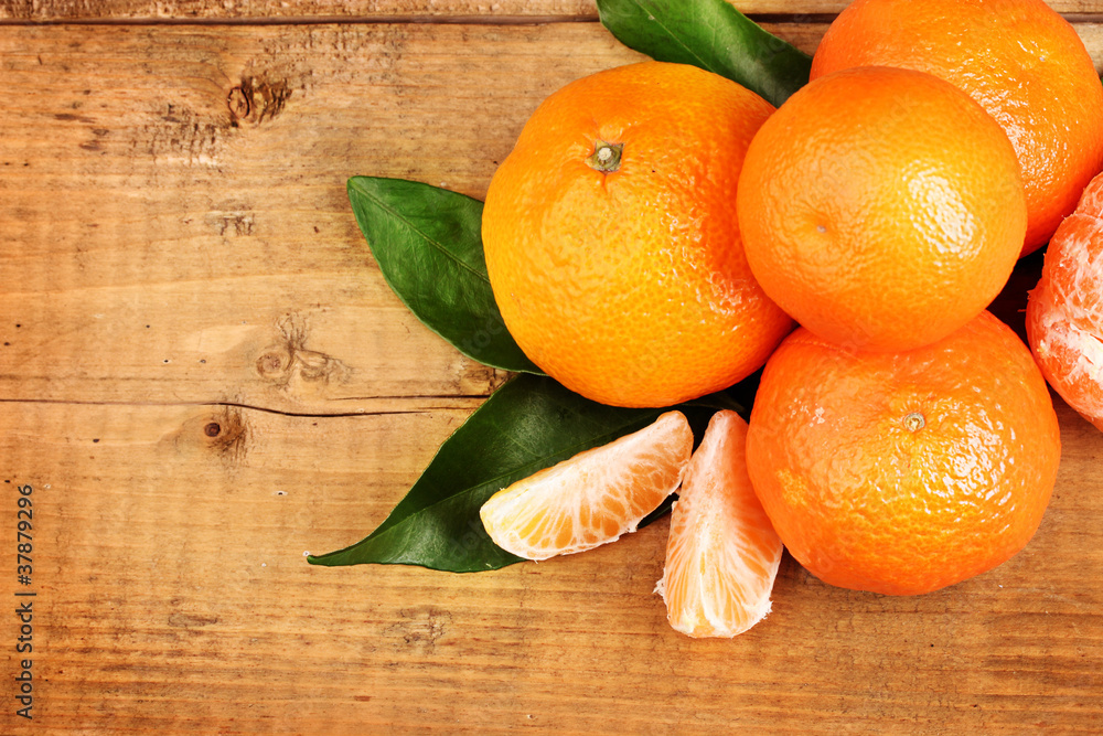 tangerines with leaves on wooden table