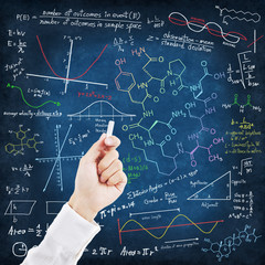 Hand writing science formulas on chalkboard