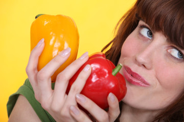 Woman holding yellow and red peppers