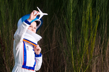 young boy playing in an astronaut suit with a toy airplane