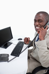 Wall Mural - Side view of a businessman answering the phone while using a mon