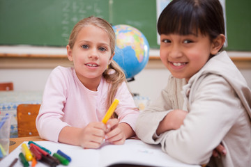 Schoolgirls drawing while looking at the camera