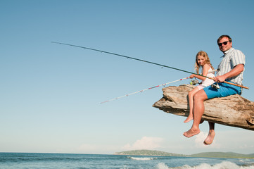 Wall Mural - Fishing - little girl fishing with father at the beach