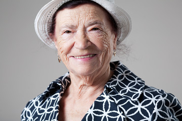 Wall Mural - Happy older lady posing on gray background.