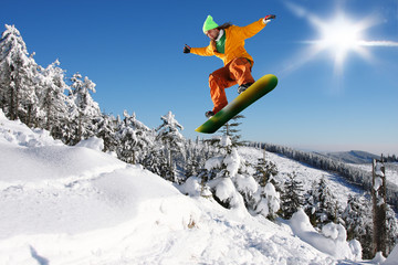 Snowboarder jumping against blue sky