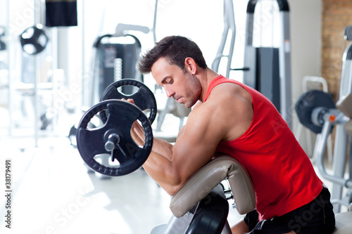 Naklejka ścienna man with weight training equipment on sport gym