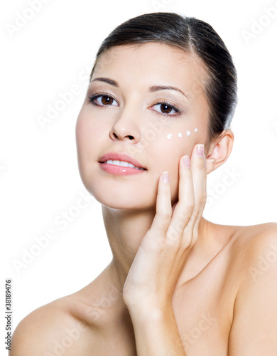 Naklejka dekoracyjna adult woman applying cosmetic cream around the eye