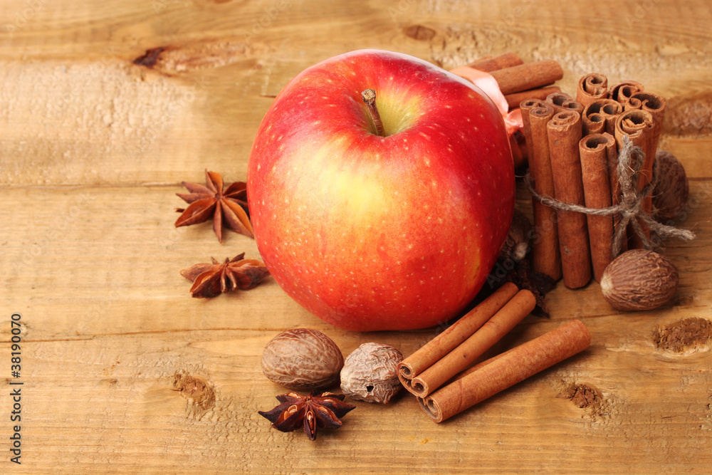 Cinnamon sticks,red apple, nutmeg,and anise on wooden table