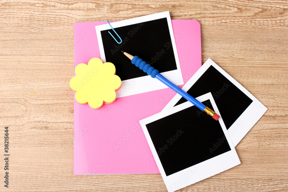 Photo papers and pink notebook on wooden background