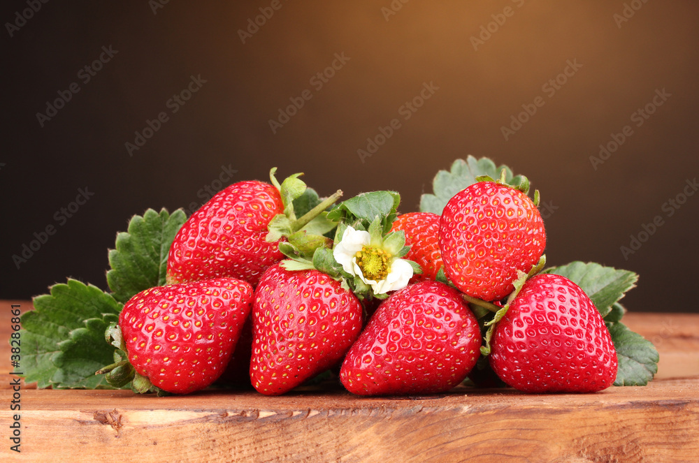 Strawberries with leaves on wooden table on brown  background