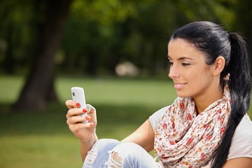 Poster - Young woman using mobile in park smiling