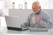 © nyul - Elderly man working on laptop smiling