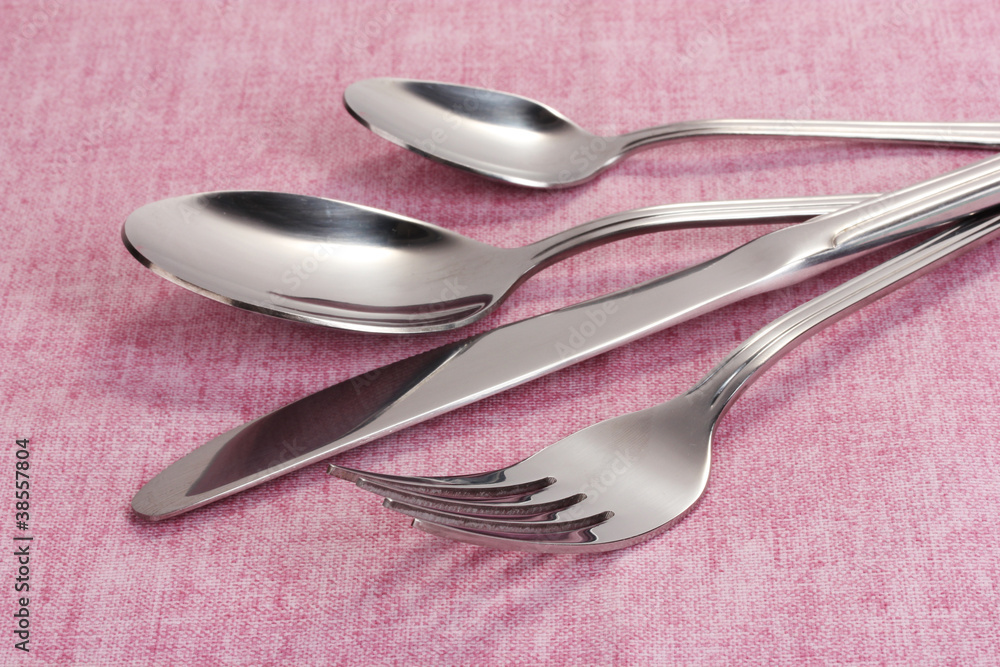 Fork, spoon and knife on a pink tablecloth