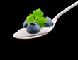 Blueberry yoghurt on a spoon garnished with 3 blueberries