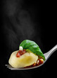 Tortellini on fork with sauce and basil