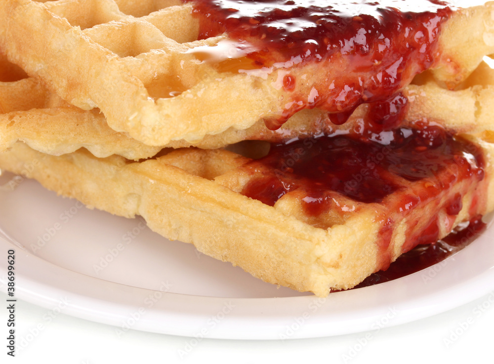 Tasty waffles with jam on plate close-up isolated on white