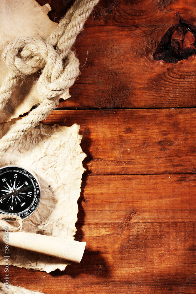 old paper, compass and rope on a wooden table