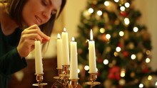 Young Woman Lighting A Candle, Christmas Tree In Background