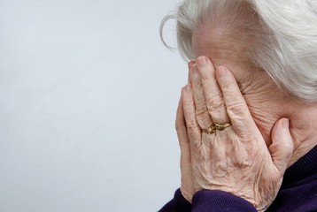 a crying elderly woman covering her face