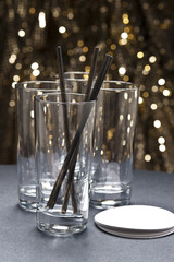 Long drink glasses with straws and coaster in front of glitter b