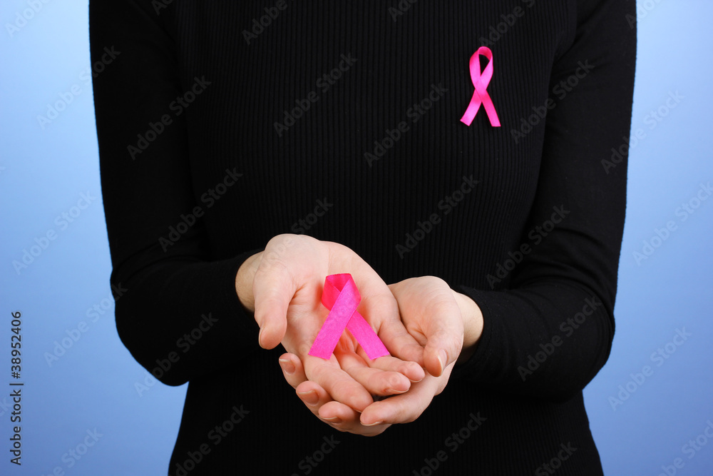 Woman with pink ribbon in hands on blue background