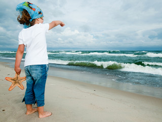 Wall Mural - Cute little girl with starfish at the beach