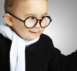 portrait of adorable kid gesturing doubt against a grey backgrou