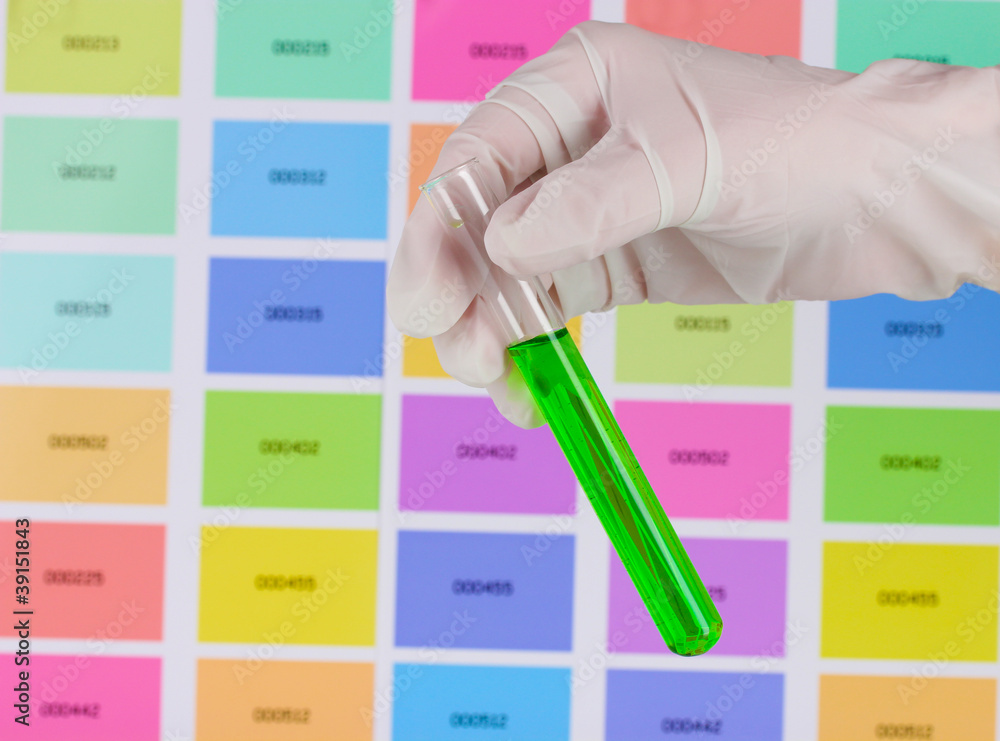 Tube with green liquid in hand on color samples background