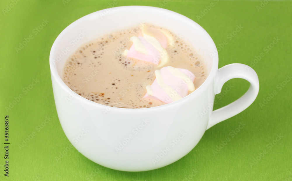 Cup of cappucino with marshmallows on green background