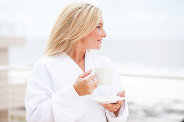 Wall Mural - beautiful young woman in bathrobe drinking coffee in the morning