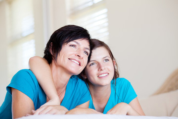 Wall Mural - mother and teen daughter lying on bed and looking into distance