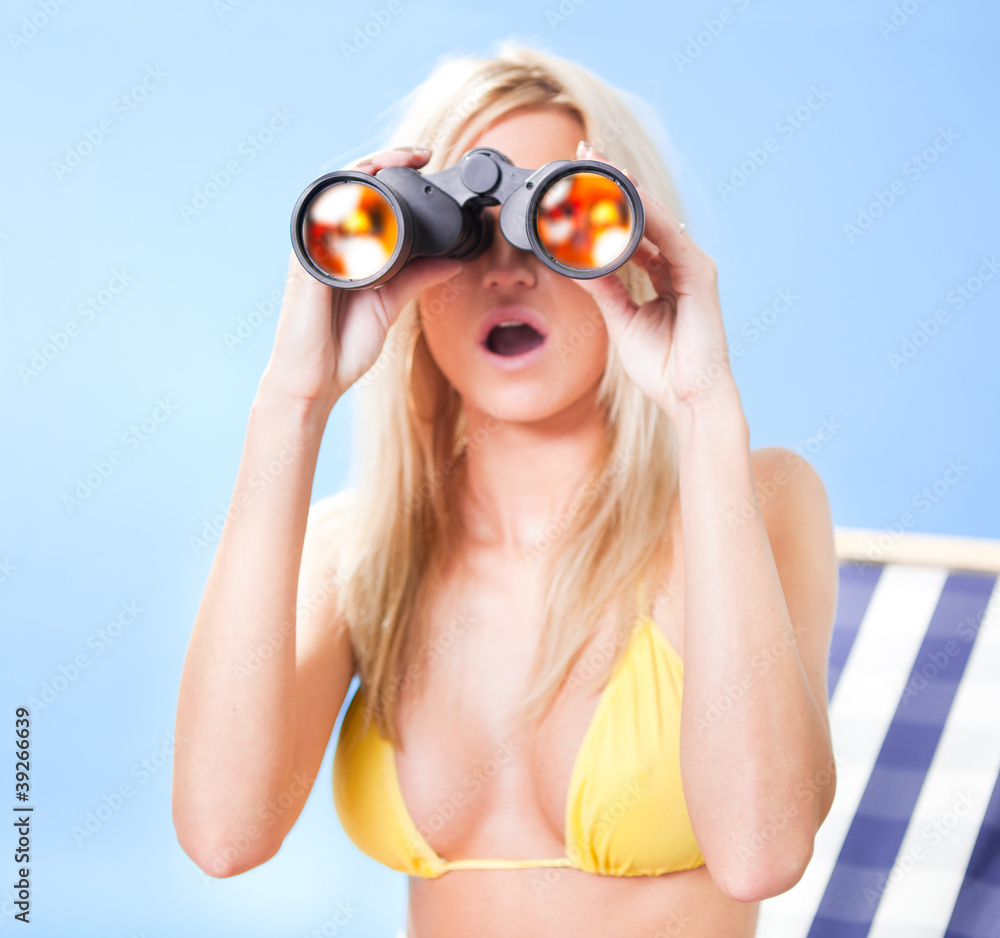 Young woman in bikini looking through binoculars