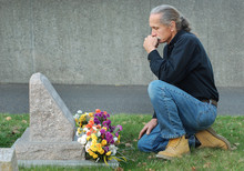 Man Sitting At Gravesite