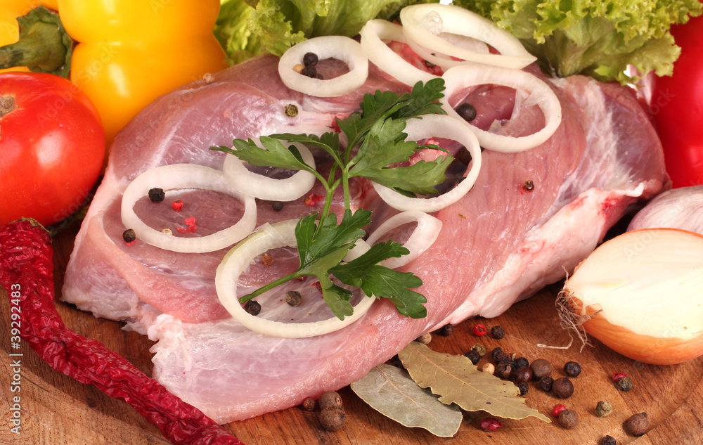 Raw meat and vegetables on a wooden board closeup